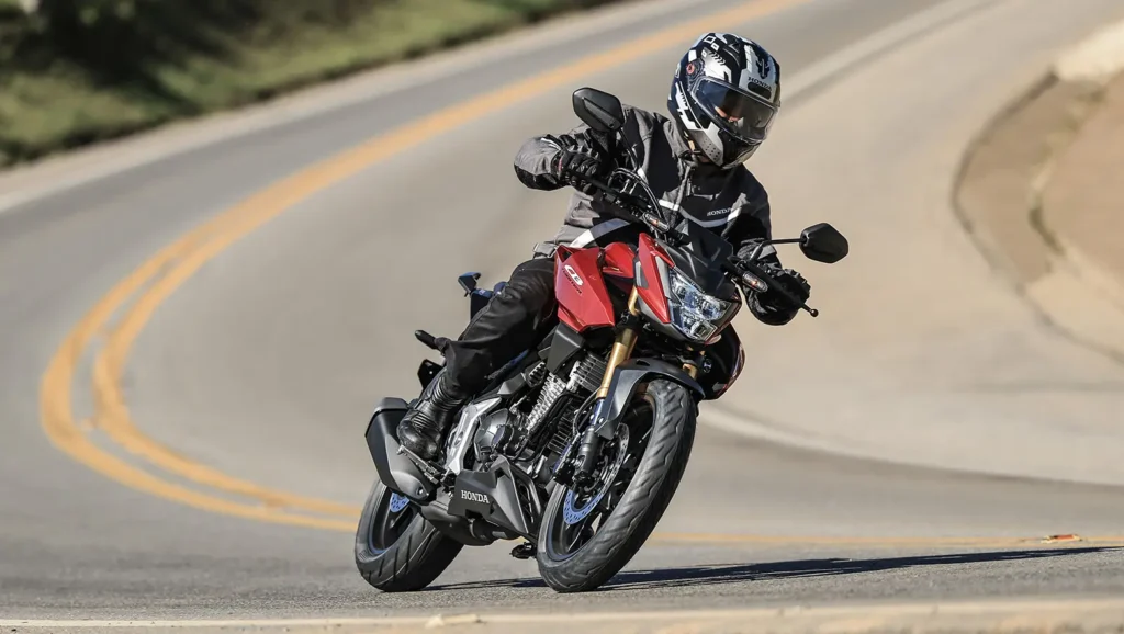 Piloto conduz Honda CB300F Twister ABS 2027 vermelha em curva.